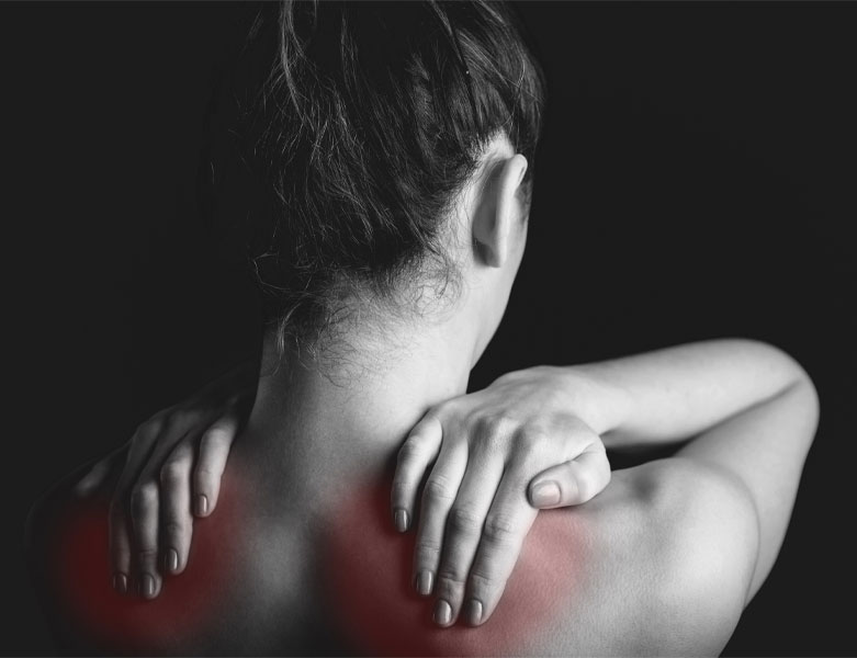 Woman rubbing sore shoulders, which are glowing red underneath her fingers. Indicates sore muscles from fibromyalgia.